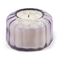 Candle in a decorative purple glass holder on a white background