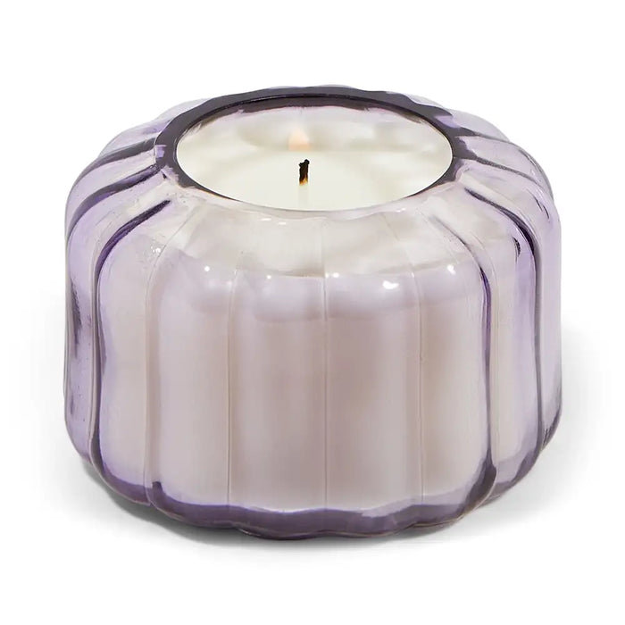 Candle in a decorative purple glass holder on a white background