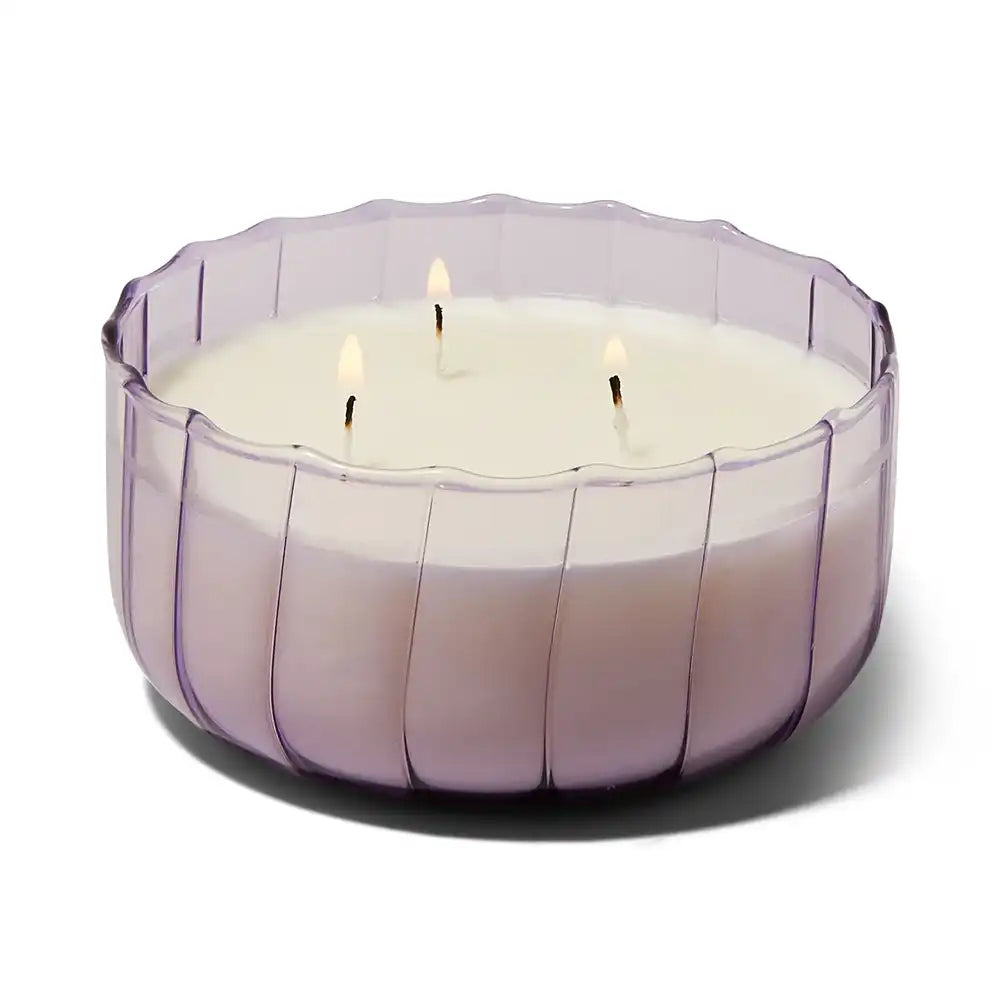Large white candle in a purple glass holder on a white background