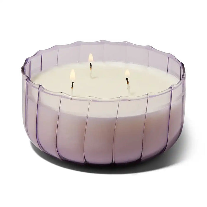 Large white candle in a purple glass holder on a white background