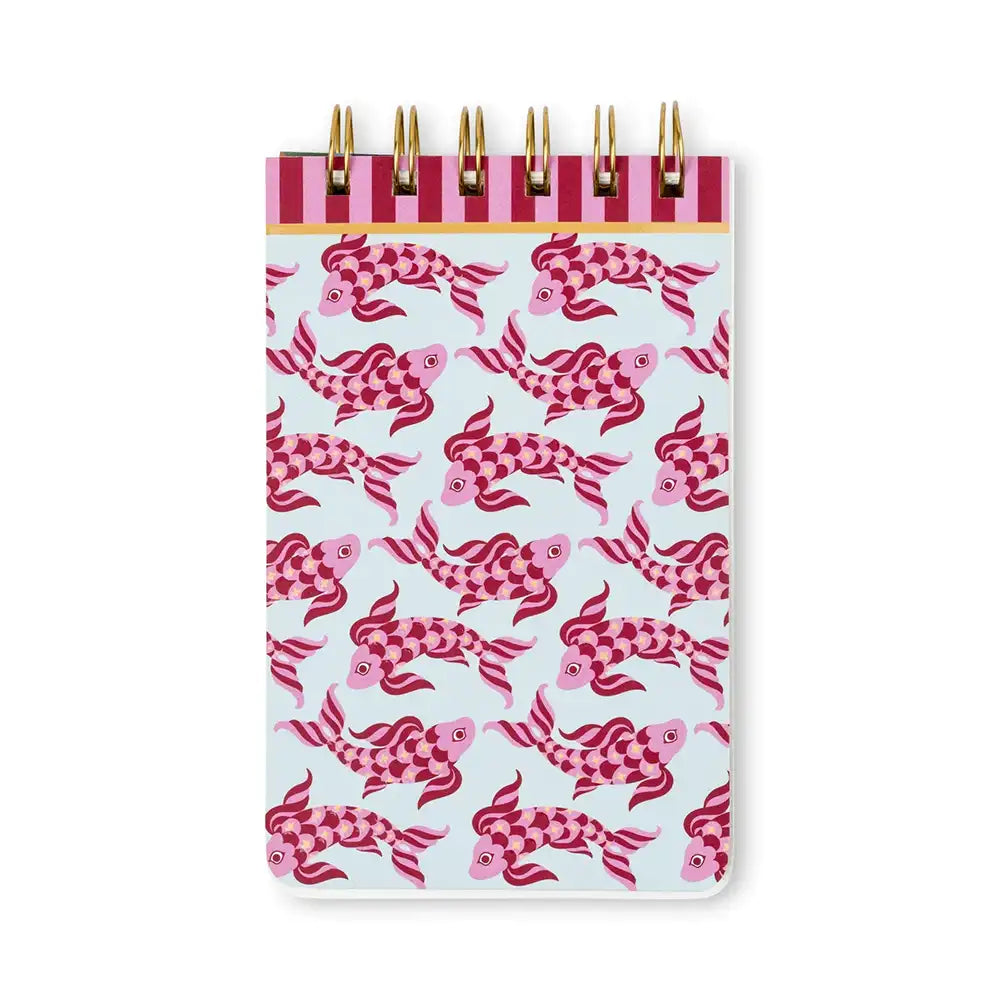 A spiral-bound notebook with a light blue cover decorated with a repeating pattern of pink and magenta koi fish. The top band features alternating dark pink and light pink stripes with gold-tone wire loops.