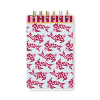 A spiral-bound notebook with a light blue cover decorated with a repeating pattern of pink and magenta koi fish. The top band features alternating dark pink and light pink stripes with gold-tone wire loops.