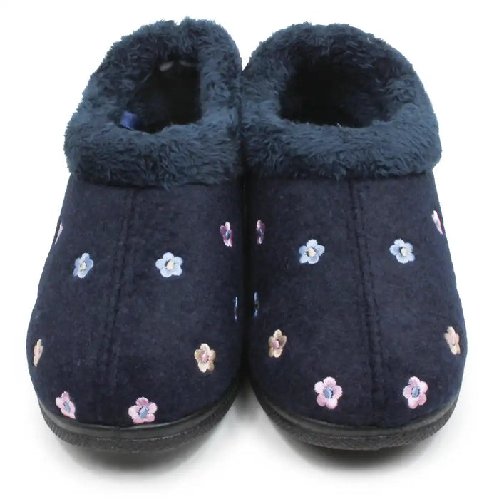 A pair of navy blue slip-on slippers with a plush navy blue lining and embroidered small flowers in pink, blue, and white, shown against a plain white background.