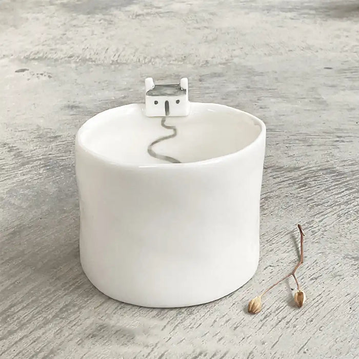 East of India tealight holder in white porcelain. Tiny house perched on the edge with a path painted leading down into the holder.