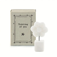 White porcelain cube base with black wire leading to white porcelain flower. Gift box in background.