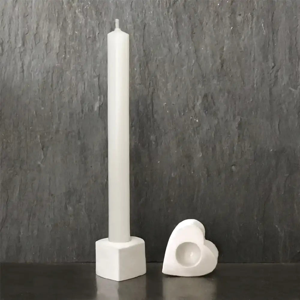 East of India heart shaped candle holder pictured on its side. White pillar candle in a cube white candle holder which is not included in the purchase.