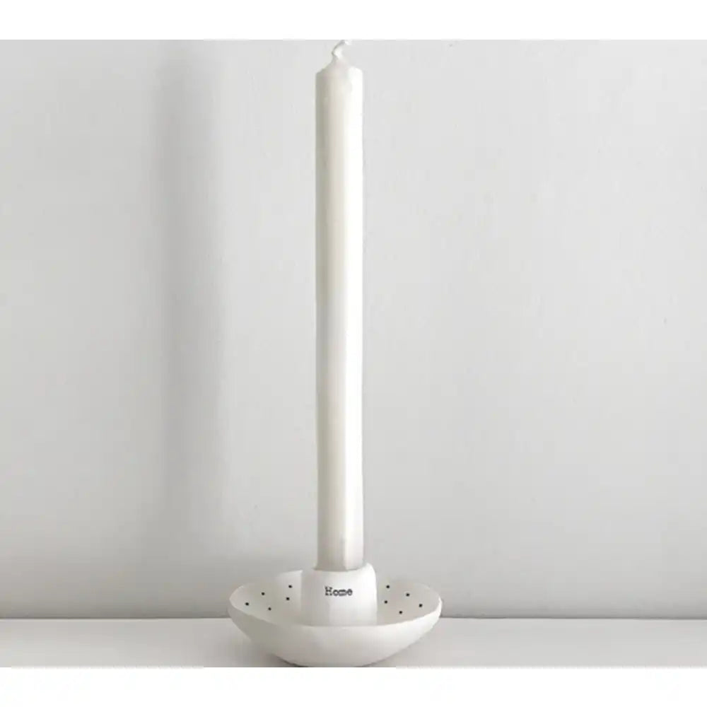 White candle holder with a white candle on a light gray background