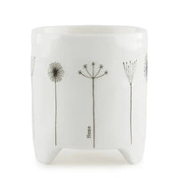 Gift box in background. White porcelain planter with black line flowers on he front and the word 'home' vertically in small text.