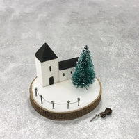 Model of a church with a Christmas tree on a textured gray surface