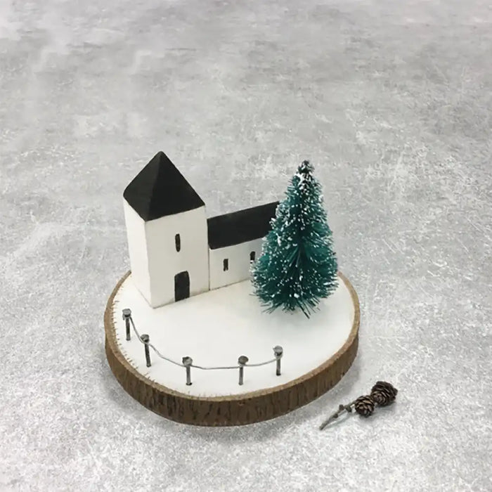 Model of a church with a Christmas tree on a textured gray surface
