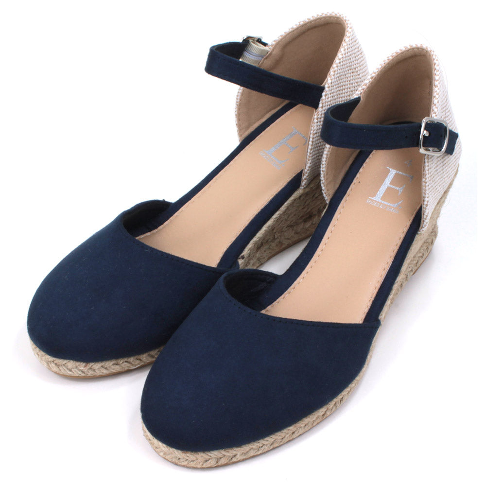 Heeled navy blue suede effect sandals. Slim ankle straps adjusted by small silver buckles. Espadrille soles. Angled view.