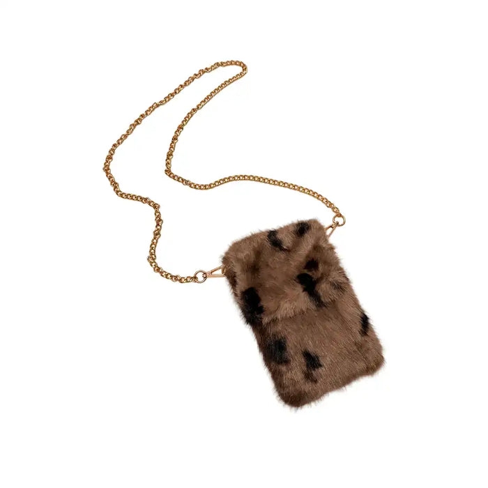 A rectangular faux fur crossbody phone bag in brown with black spots, attached to a gold chain strap, shown on a plain white background.