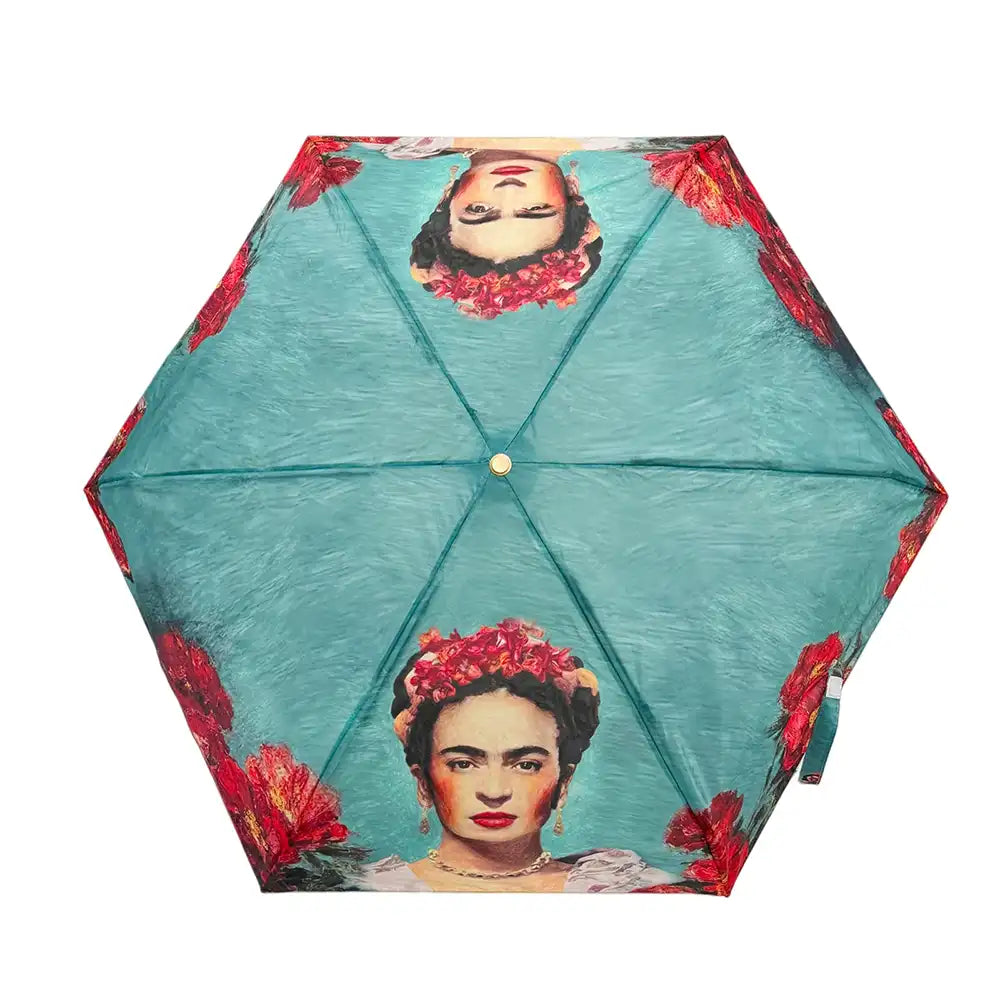 A hexagonal umbrella shown from above on a white background, featuring a teal-blue painted texture with printed portraits of Frida Kahlo wearing red flower crowns and red floral motifs along the edges.
