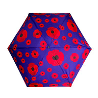 A top-down view of a compact umbrella with a vibrant purple canopy decorated with a repeating pattern of red poppies with black centers, isolated on a white background.