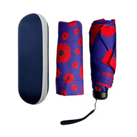 A folded umbrella shown in three views on a white background: the closed navy fabric cover on the left, the unfolded patterned fabric body in the center, and the folded umbrella with visible handle and wrist strap on the right. The fabric features a bold red poppy pattern on a purple background.