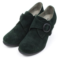 Fly London oil suede heeled shoes in pine green. Cross over strap with dark metal buckle. Decorative stitching over the toes. Angled view.