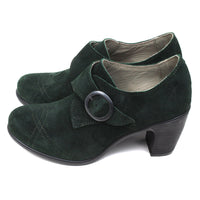 Fly London oil suede heeled shoes in pine green. Cross over strap with dark metal buckle. Decorative stitching over the toes. Side view.