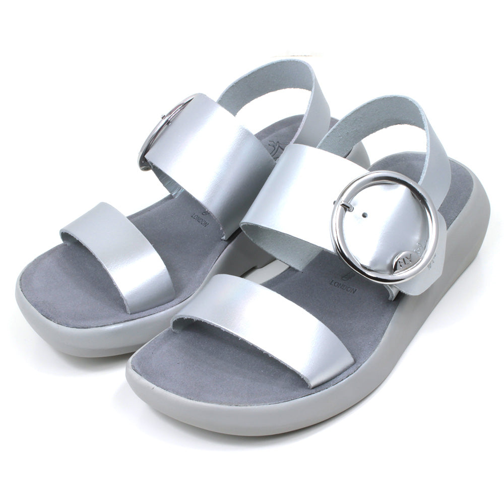 Fly London Mirror sandals in silver colour. Grey soles and footbeds. Large silver buckles on foot strap. Angled view