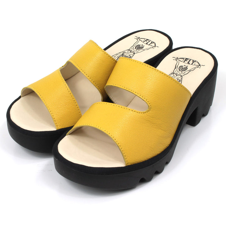 Fly London Mousse mule style sandals in yellow leather. Black chunky rubber heels and soles. Angled view