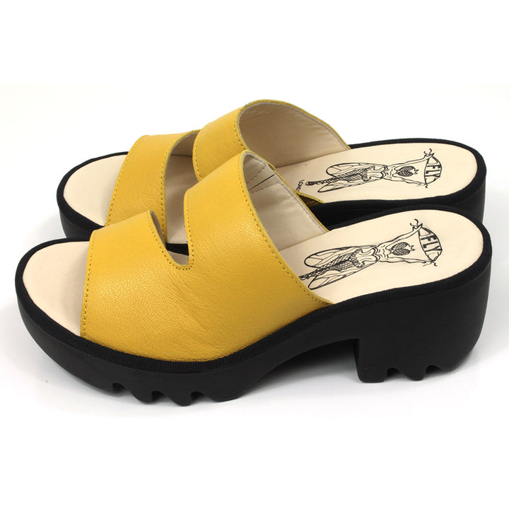 Fly London Mousse mule style sandals in yellow leather. Black chunky rubber heels and soles. Side view