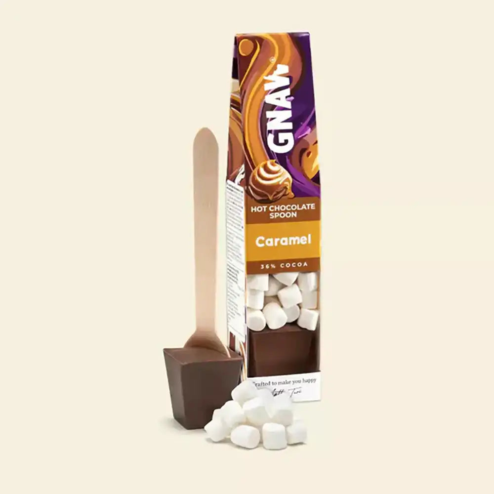 Gnaw Caramel hot chocolate spoon packaging with a spoon and marshmallows on a beige background