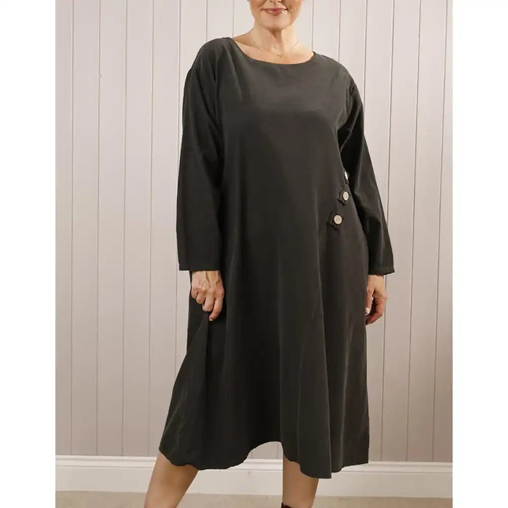 Woman wearing a black dress with buttons against a wooden panel background