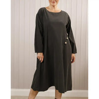 Woman wearing a black dress with buttons against a wooden panel background