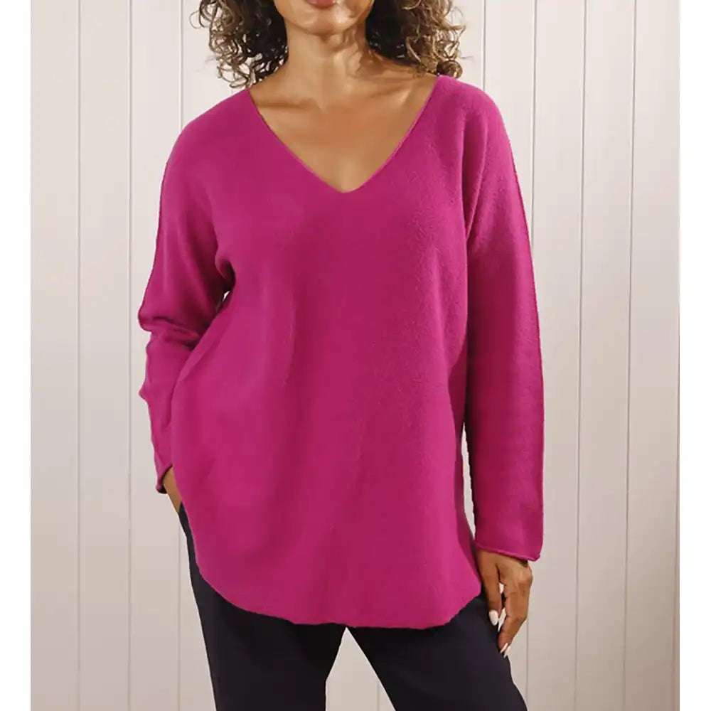 Person wearing a bright pink sweater against a neutral background