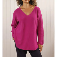 Person wearing a bright pink sweater against a neutral background