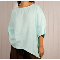 Person wearing a light blue poncho against a wooden panel background