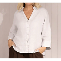 Person wearing a white button-up shirt with rolled-up sleeves against a neutral background