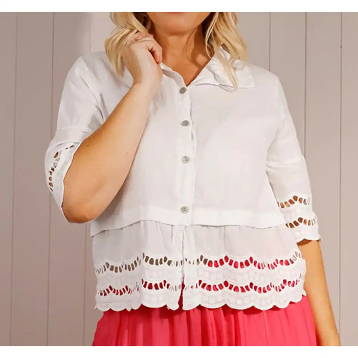 White blouse with lace details worn by a person against a neutral background