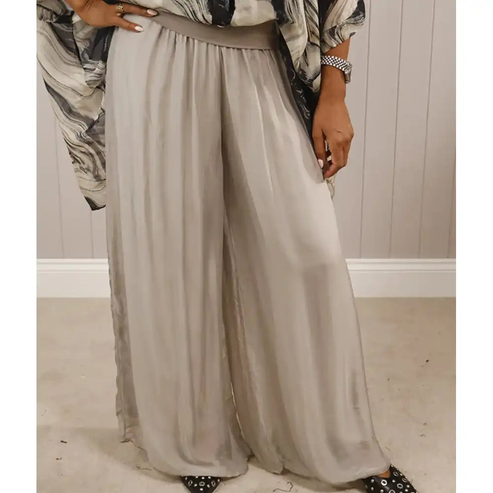 Person wearing a long, light gray skirt with a patterned top in a neutral setting.