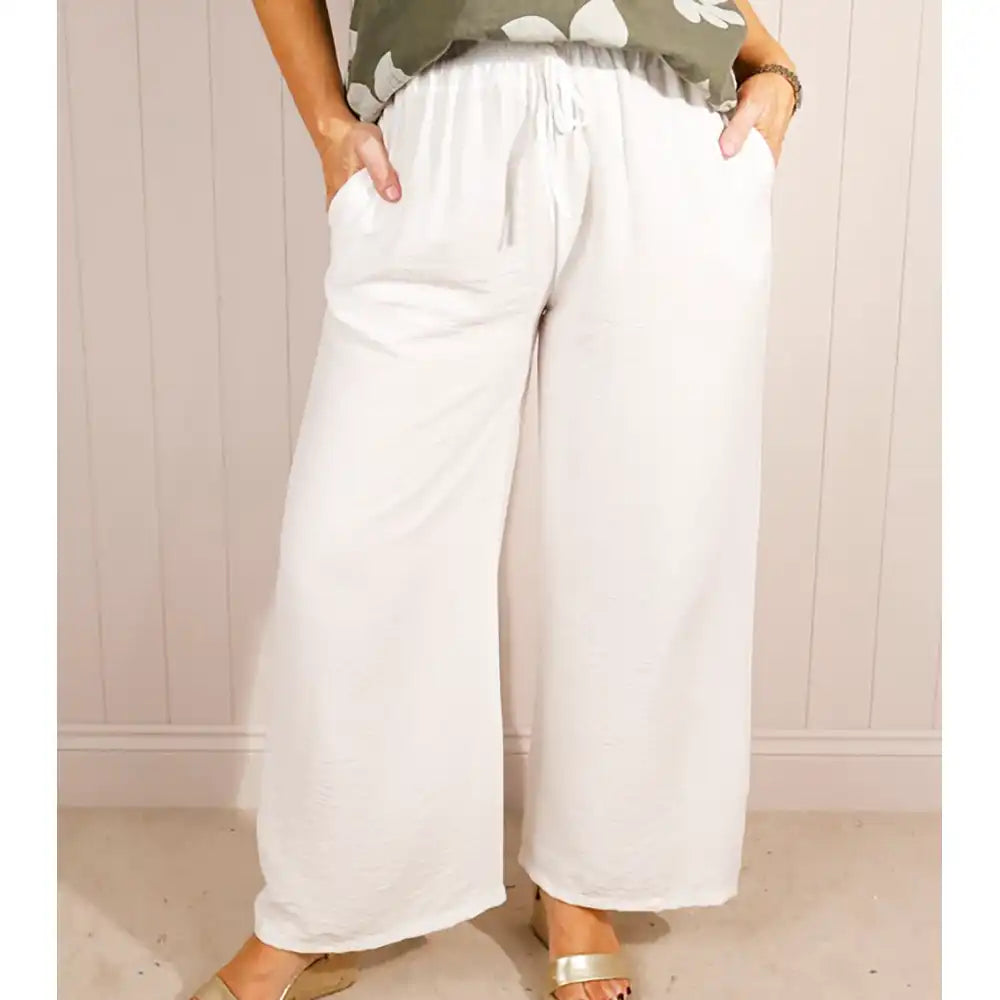 Person wearing white wide-leg pants with a neutral background