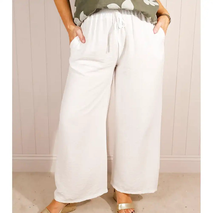 Person wearing white wide-leg pants with a neutral background