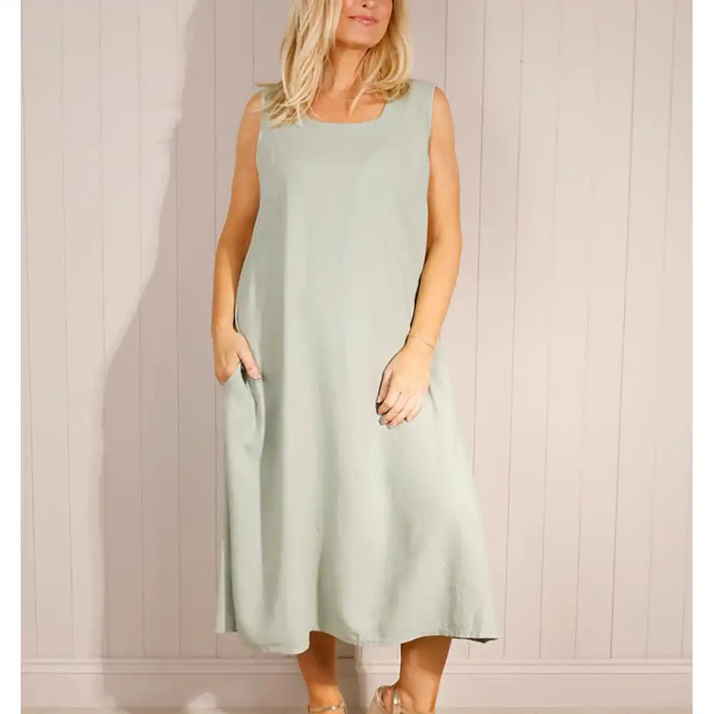 Woman wearing a light blue sleeveless dress against a plain background