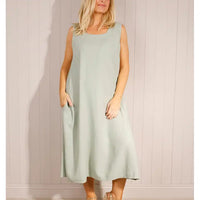 Woman wearing a light blue sleeveless dress against a plain background