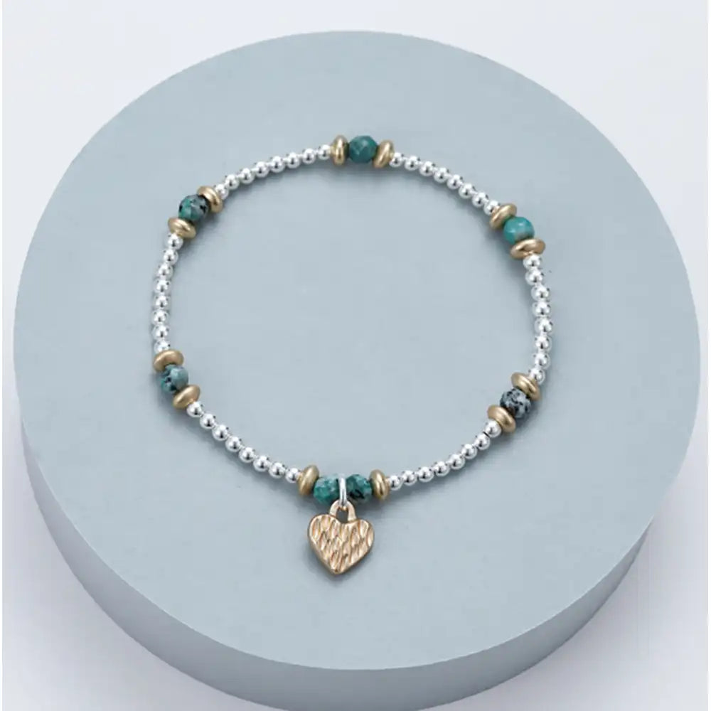 Bracelet with heart charm on a light blue circular stand