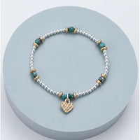 Bracelet with heart charm on a light blue circular stand