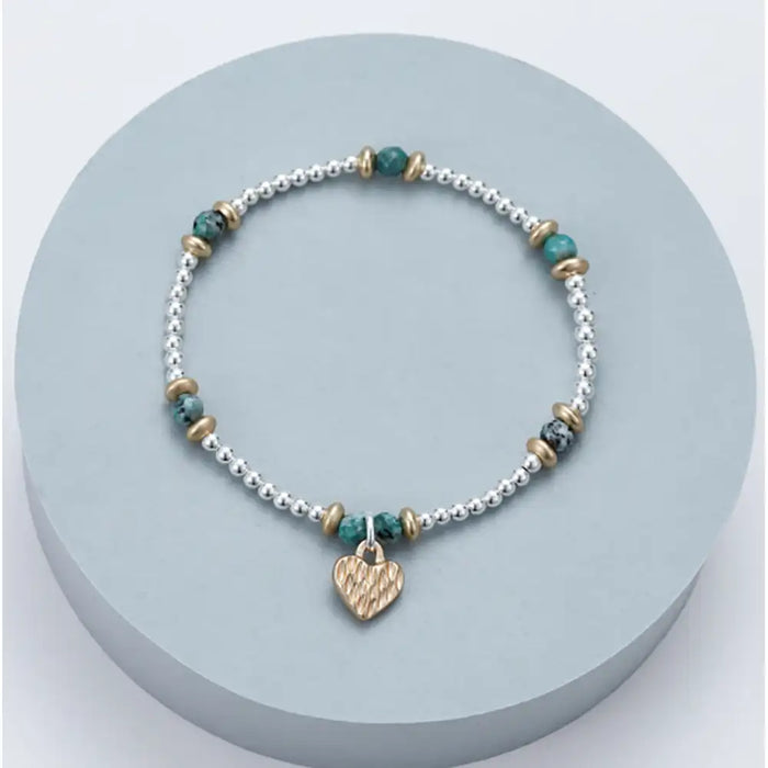 Bracelet with heart charm on a light blue circular stand