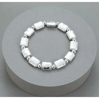 A sterling silver beaded stretch bracelet with rectangular and round beads, displayed on a round gray pedestal.