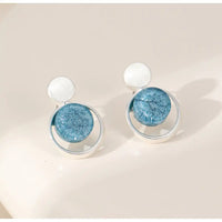 Pair of earrings with blue circular stones on a beige background
