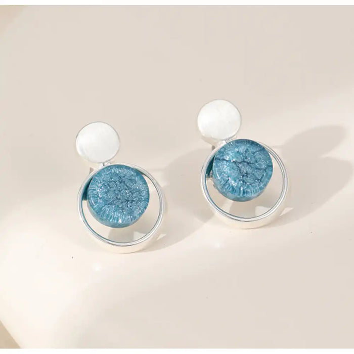Pair of earrings with blue circular stones on a beige background