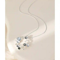 Silver chain with a hoop pendant. The pendant has hollow dimples with different shade of grey.