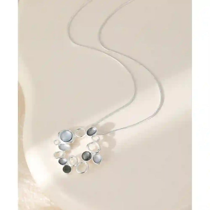 Silver chain with a hoop pendant. The pendant has hollow dimples with different shade of grey.