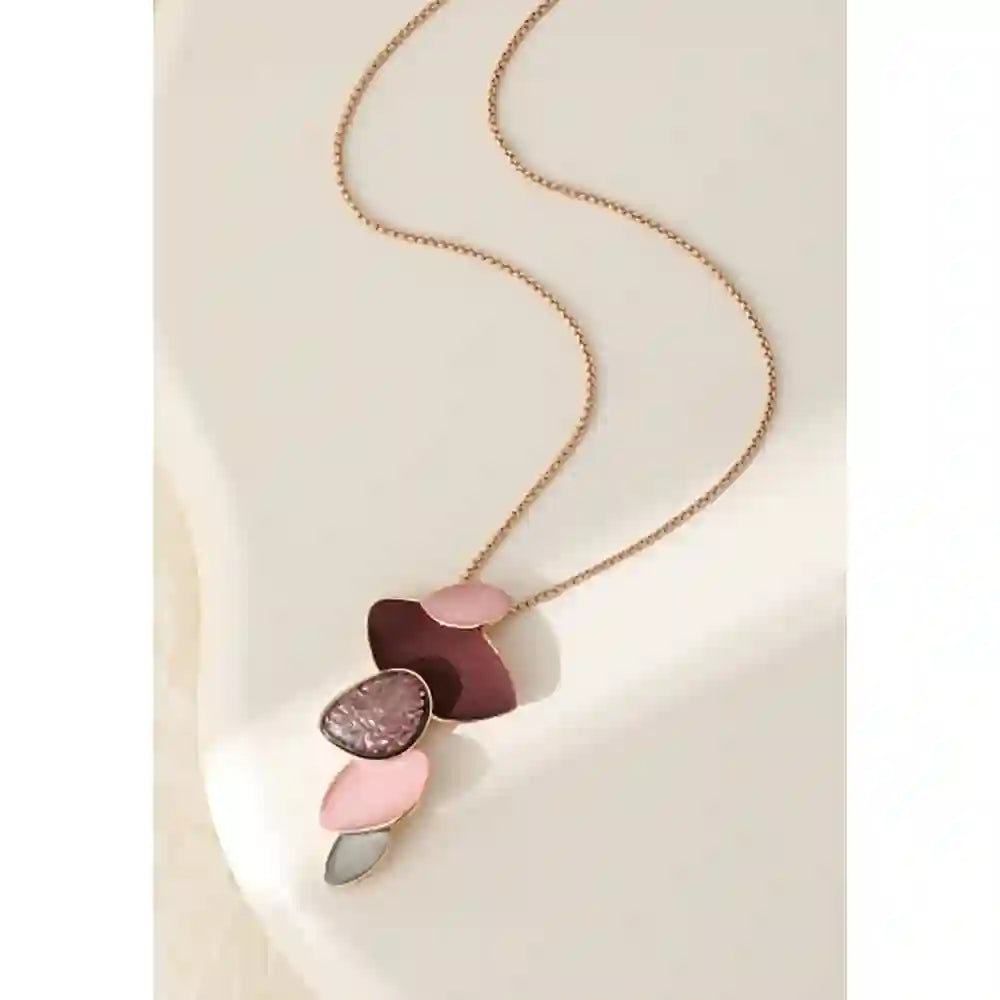 A gold chain necklace with a multi-colored abstract pendant made of overlapping petal-like shapes in pink, burgundy, mauve, and gray, displayed on a light cream background.