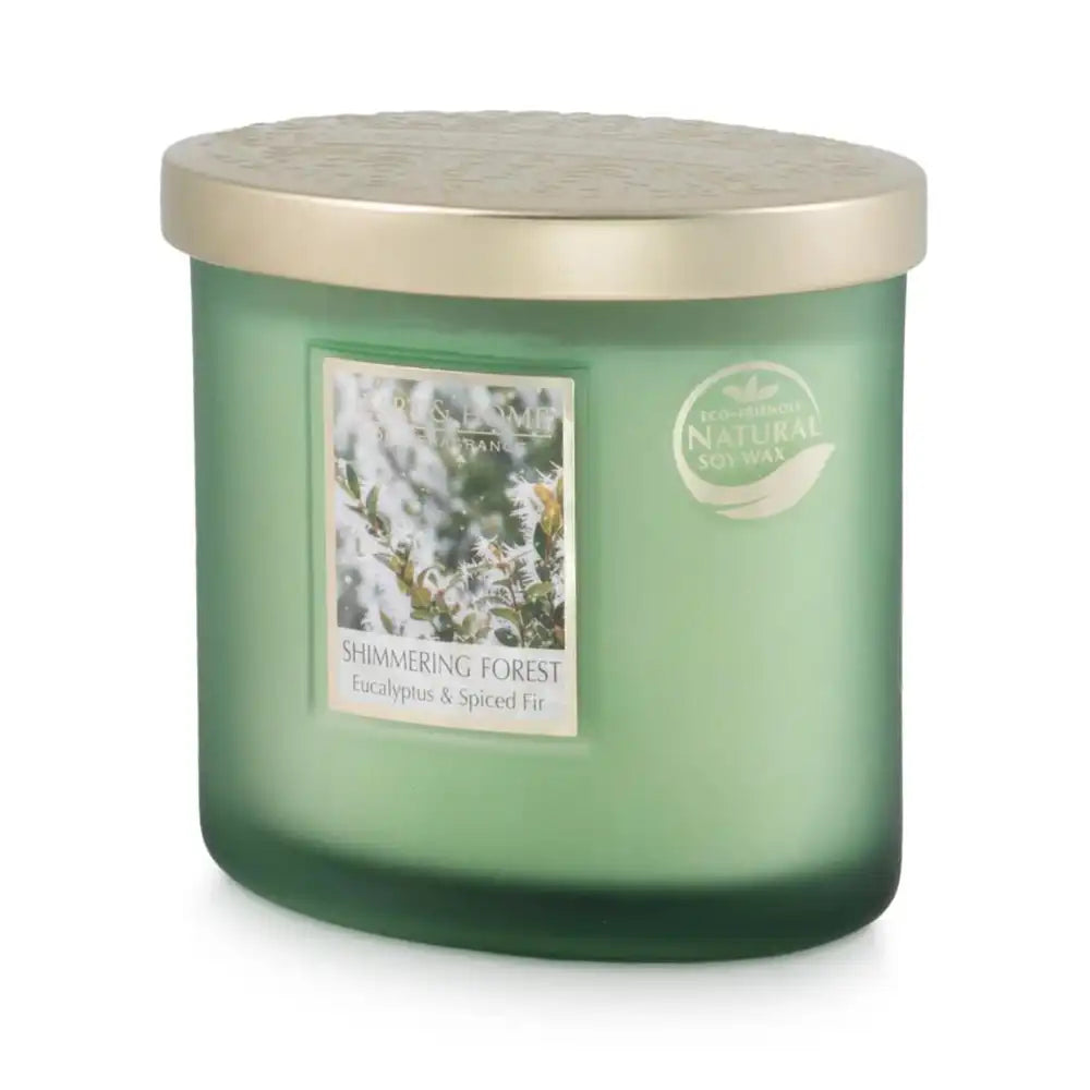A green glass jar candle with a metallic gold lid, featuring a label that reads 'Shimmering Forest' and 'Eucalyptus & Spiced Fir'.