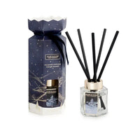 Heart & Home Christmas Fragrance Diffuser set featuring a dark blue gift box with a gold cap and reeds, alongside the clear glass diffuser bottle with black reeds and a gold collar, on a white background.