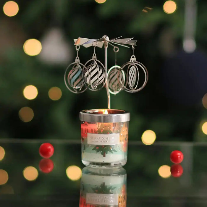 Candle with hanging silver ornaments against a blurred Christmas tree background