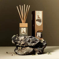 A diffuser set with wooden sticks and packaging on a dark background